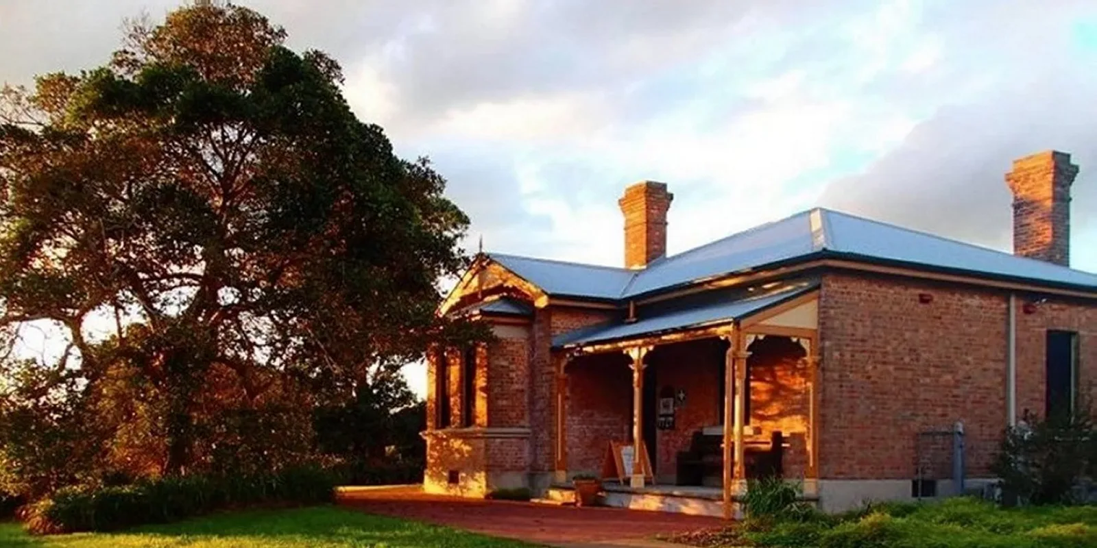 The double-brick Schoolmasters House with its chimneys and verandah at golden hour
