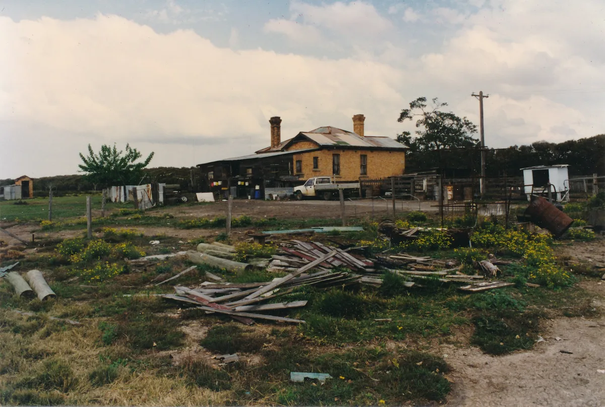 Salvaged timber piled in the yard in front of the house and its sheds