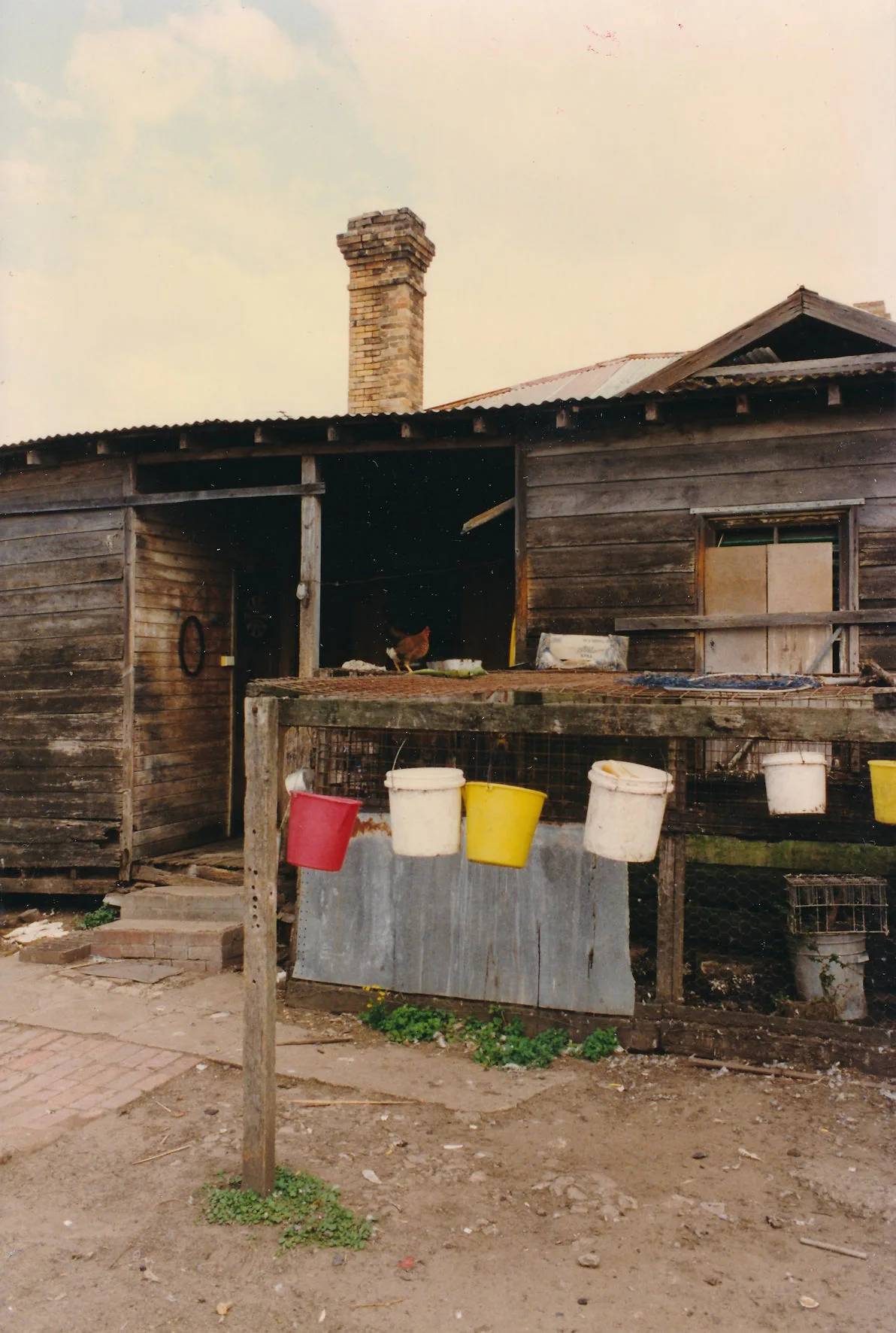 The brick chimney rising over the farmyard sheds, photographed in portrait