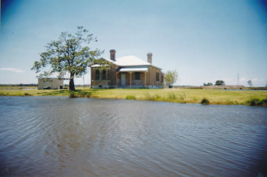 The house on its grass rise completely ringed by floodwater